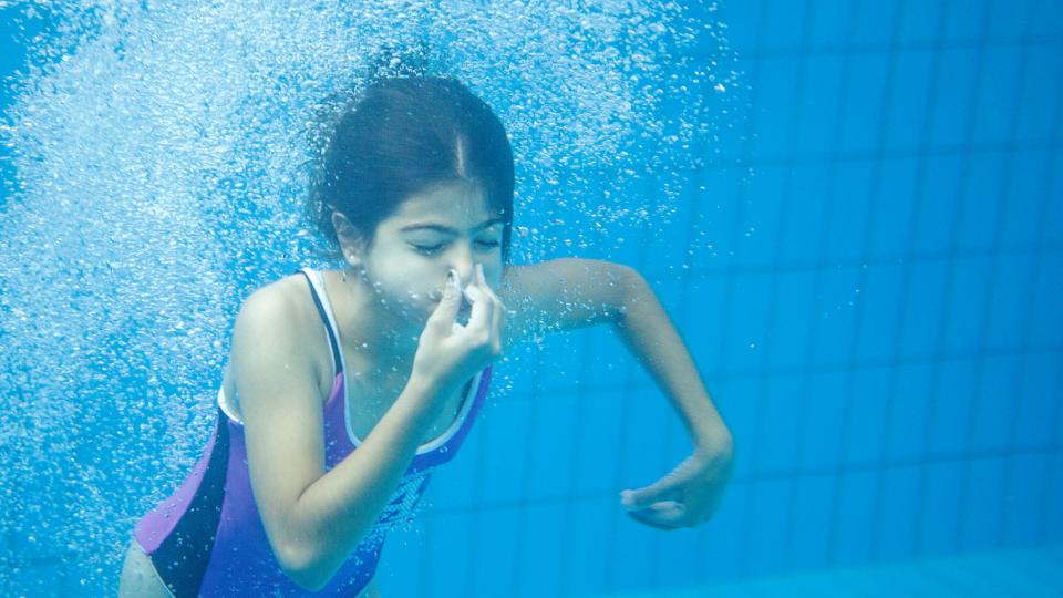Kind taucht unter Wasser und hält sich die Nase zu