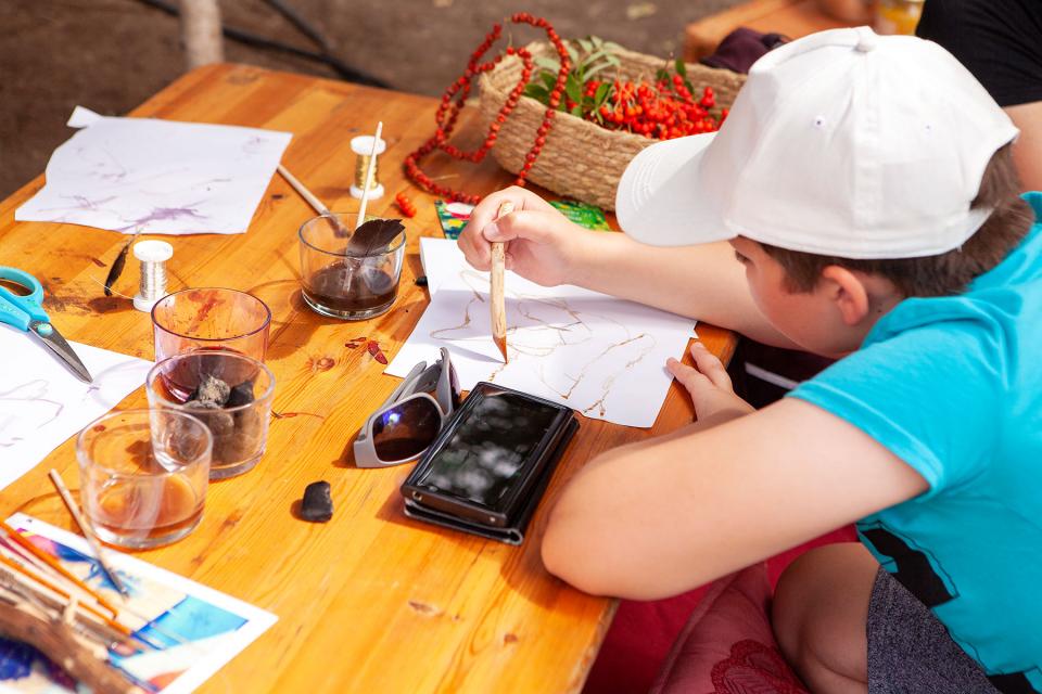 Ein Kind malt mit Tinte und Holzfeder