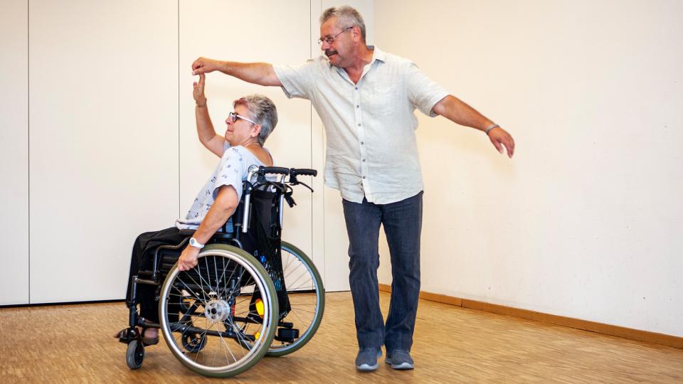 Eine Rollstuhlfahrerin und ein Fußgänger tanzen.