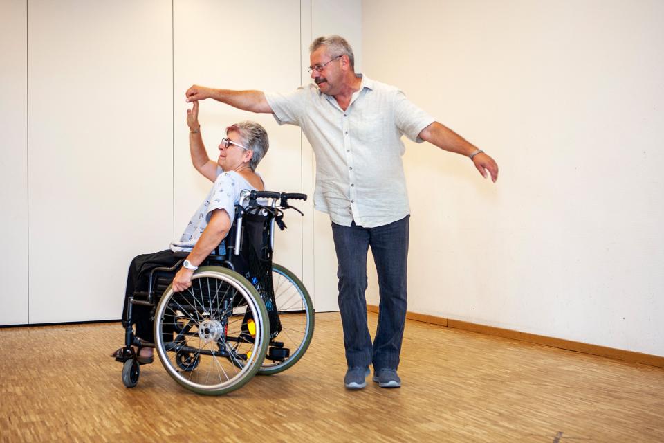eine Person im Rollstuhl tanzt mit einer anderen Person, nicht im Rollstuhl