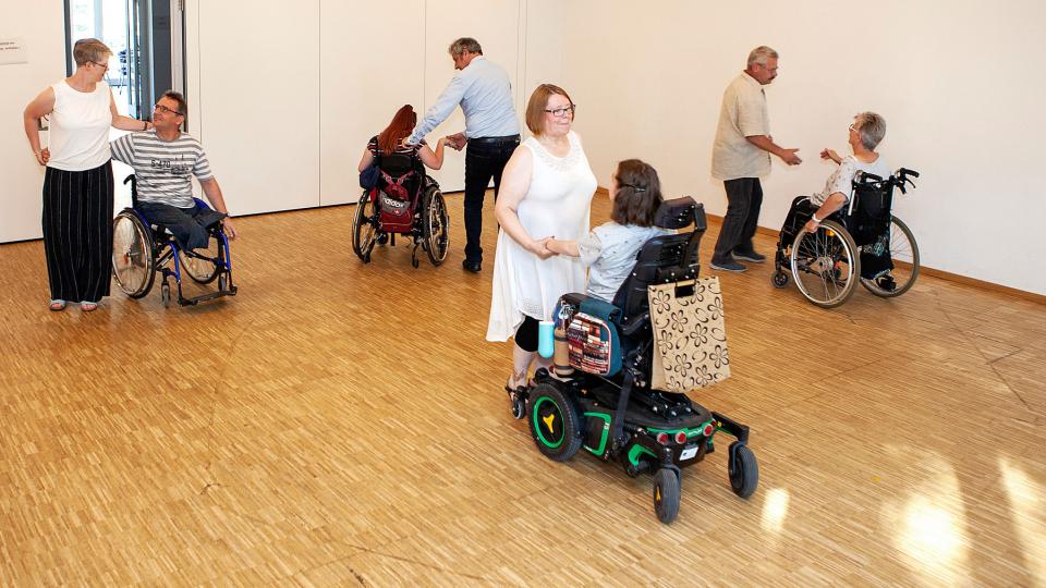 Vier Tanzpaare, jeweils eine Person im Rollstuhl, tanzen gemeinsam