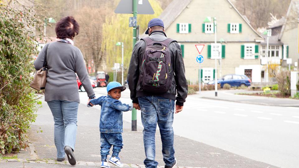 Generationen Hand in Hand – Kind und Eltern gehen Straße entlang