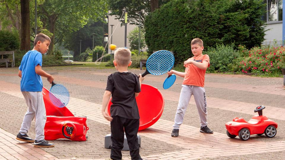 Kinder spielen mit Ball und Schlägern auf einem Platz
