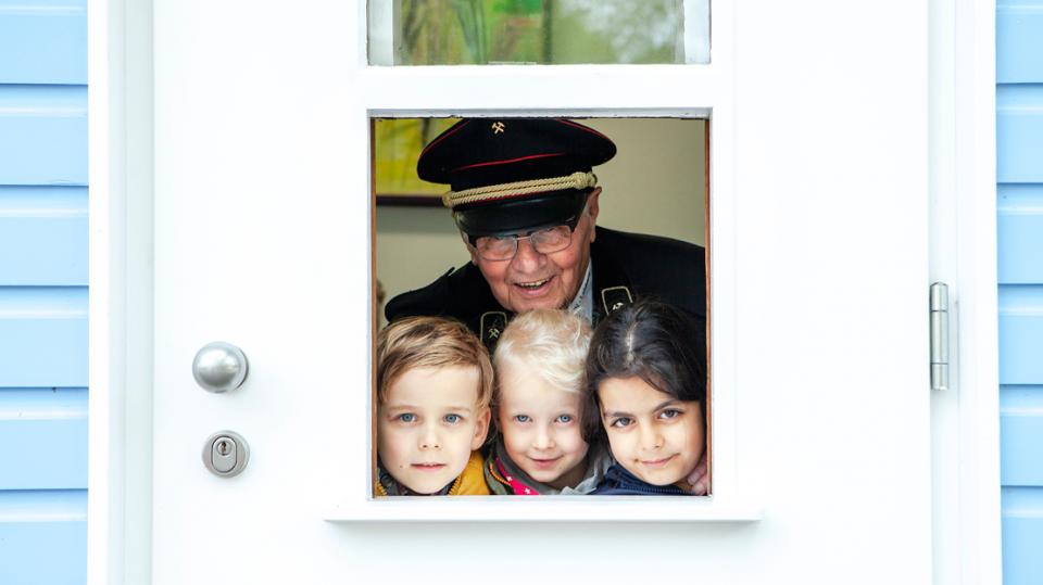 Blaue Bude: Hermann Dolar (Knappenverein) schaut mit Kindern durch Türfenster der Blauen Bude
