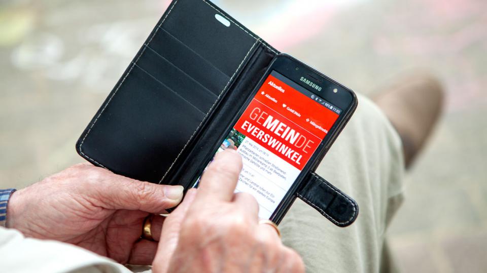 Älterer Mann bedient Everswinkel-App auf Smartphone
