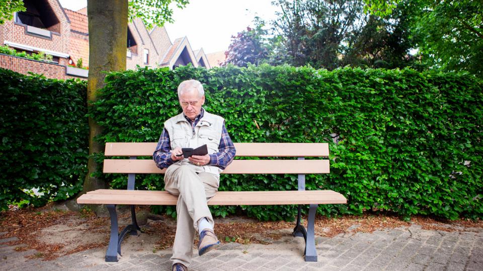Everswinkel: Mann sitzt auf Bank und nutzt sein Smartphone