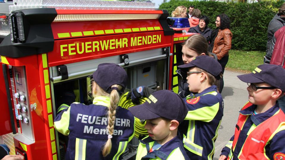 Kinder in Uniformen der Feuerwehr Menden beladen die Miniaturausgabe eines Löschfahrzeugs.