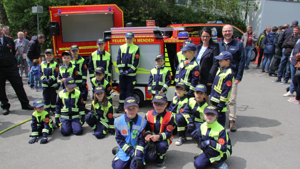 Gruppenbild von Feuerwehrkindern vor einem Mini-Löschfahrzeug.