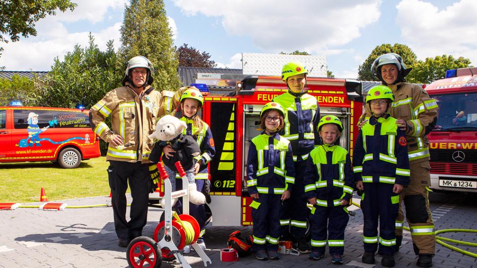Kleine Gruppe von Feuerwehrkindern vor einem Mini-Löschfahrzeug