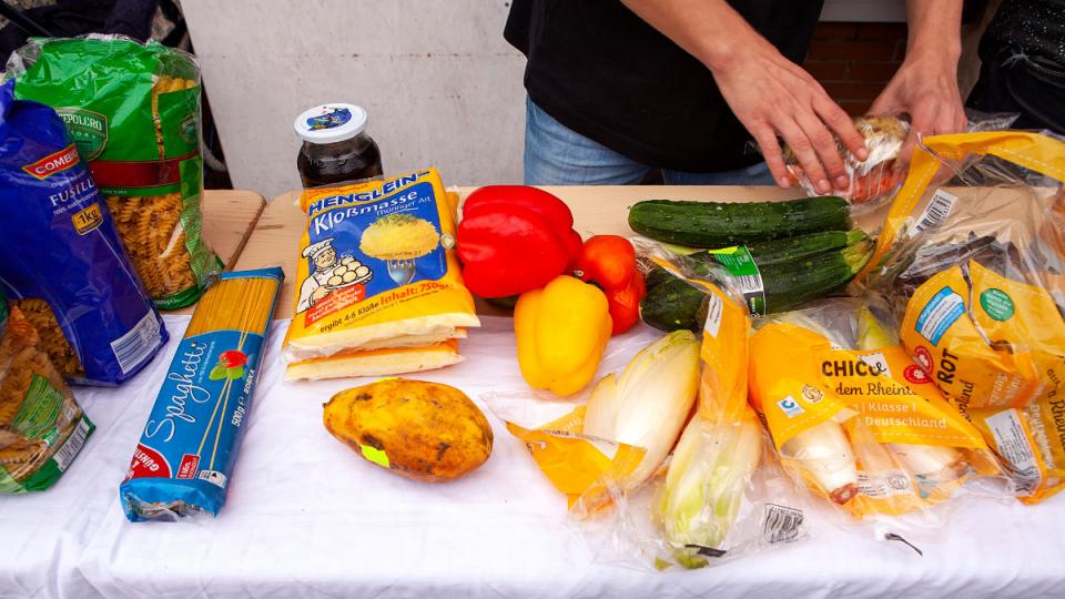 Tisch mit Lebensmitteln und Hände einer Person, die etwas verpackt