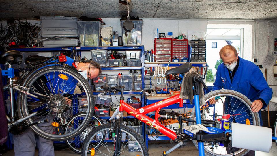 Zwei Männer arbeiten jeweils an einem Fahrrad in der Werkstatt