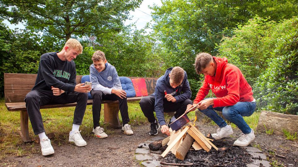 Vier Jugendliche an einer Feuerstelle