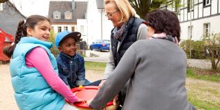 Generationen Hand in Hand – Kinder und Frauen gemeinsam auf Spielplatz