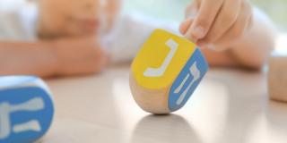 Junge spielt mit Kreisel, auf dessen Seiten hebräische Buchstaben gemalt sind