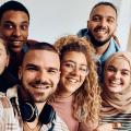 Symbolfoto: Gruppe aus sechs verschiedenen jungen Menschen, die arabisch gelesen werden können und froh in die Kamera im Selfie-Modus winken